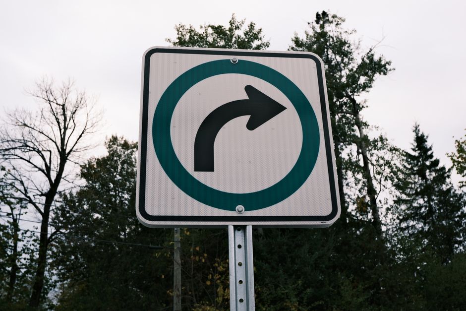 A right turn traffic sign against a backdrop of trees captured outdoors.