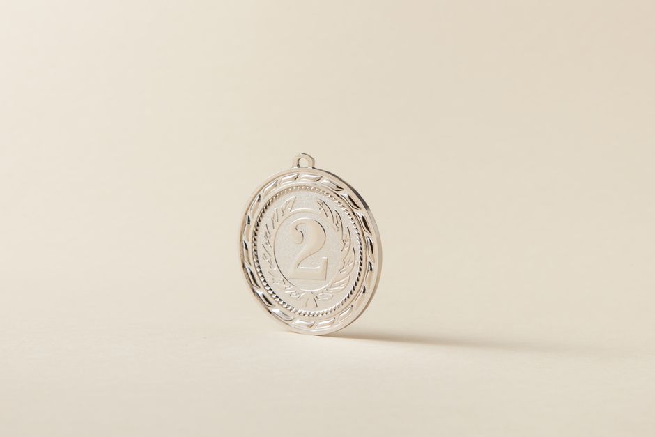 A shiny silver medal featuring the number two on a neutral, light background.