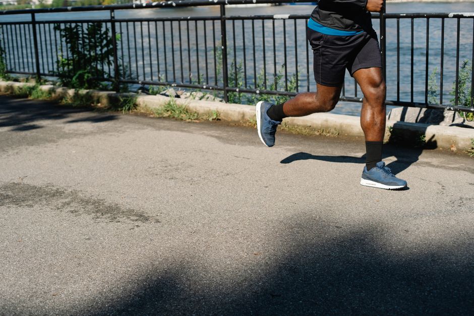 Athletic man running along a riverside path, promoting healthy living and exercise outdoors.