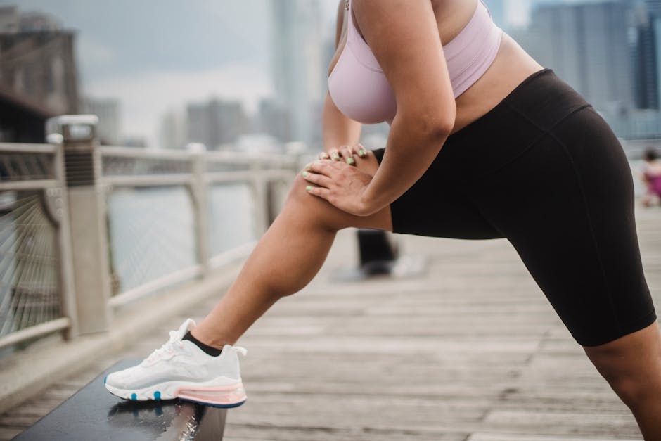 Woman stretching on a city boardwalk in activewear, promoting fitness and healthy lifestyle.