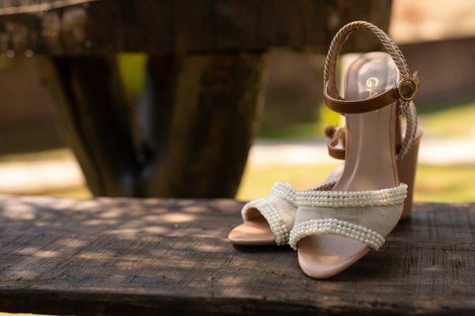 Stylish beige sandals adorned with pearls, captured in natural outdoor setting.