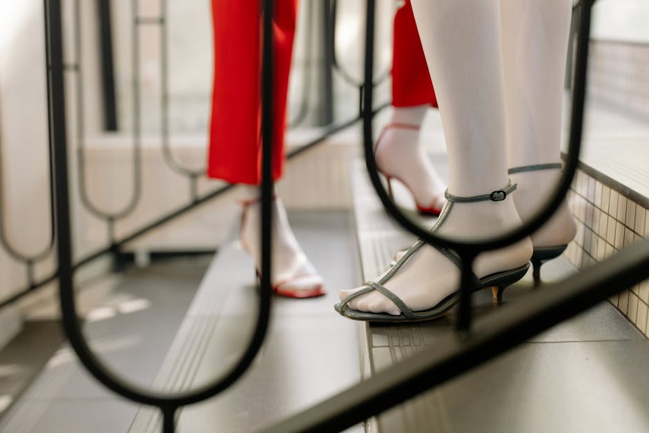 Close-up of stylish women in high heels ascending modern indoor stairs.
