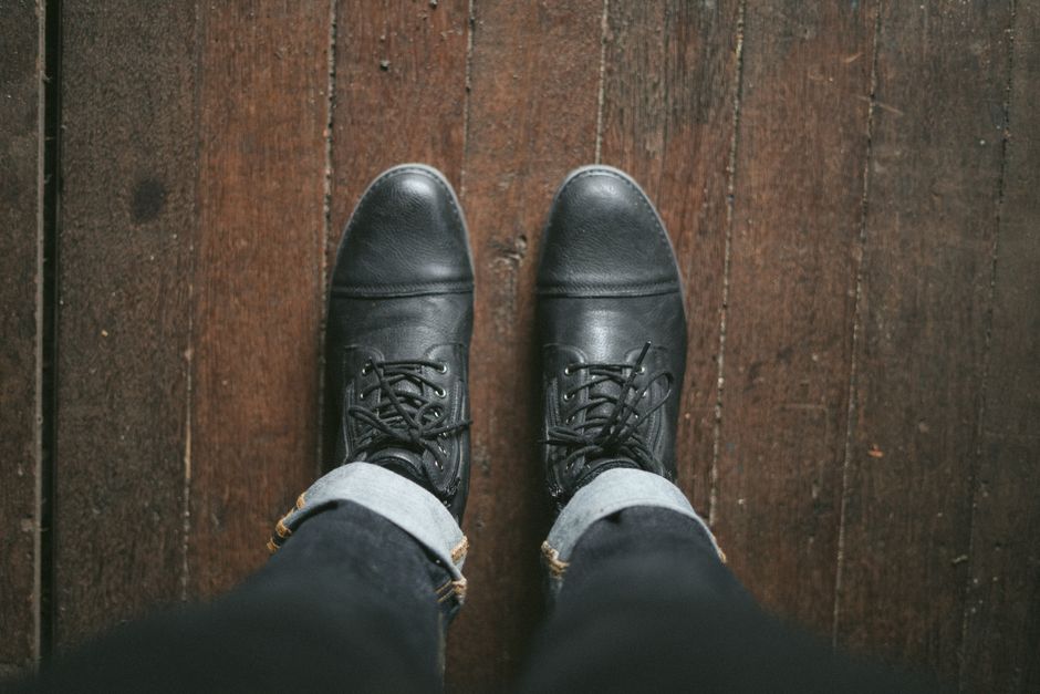 Black leather shoes viewed from above on a vintage wooden floor.