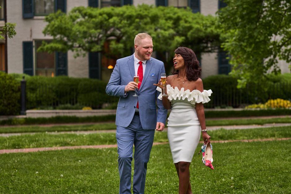 A well-dressed couple enjoys drinks in a scenic garden setting, exuding elegance and joy.