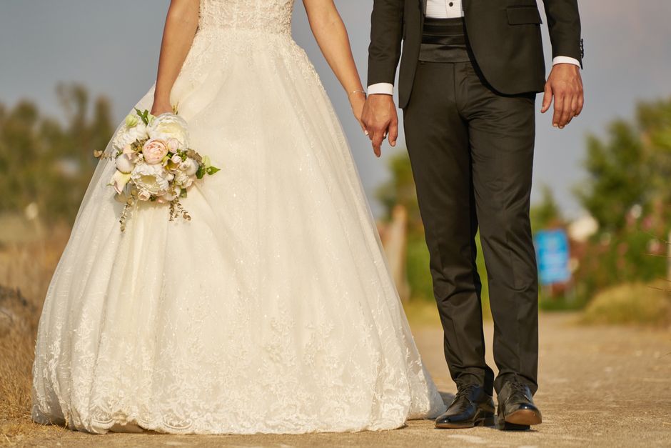 A romantic outdoor wedding of a bride and groom holding hands.