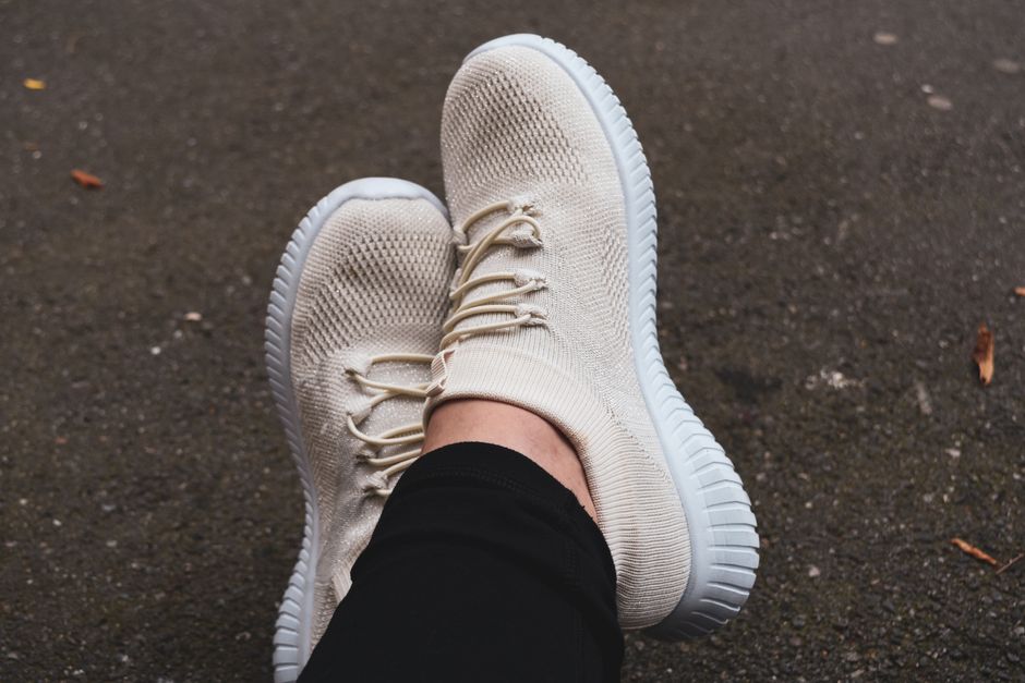 Fashionable cream sneakers on pavement, showcasing casual urban style.