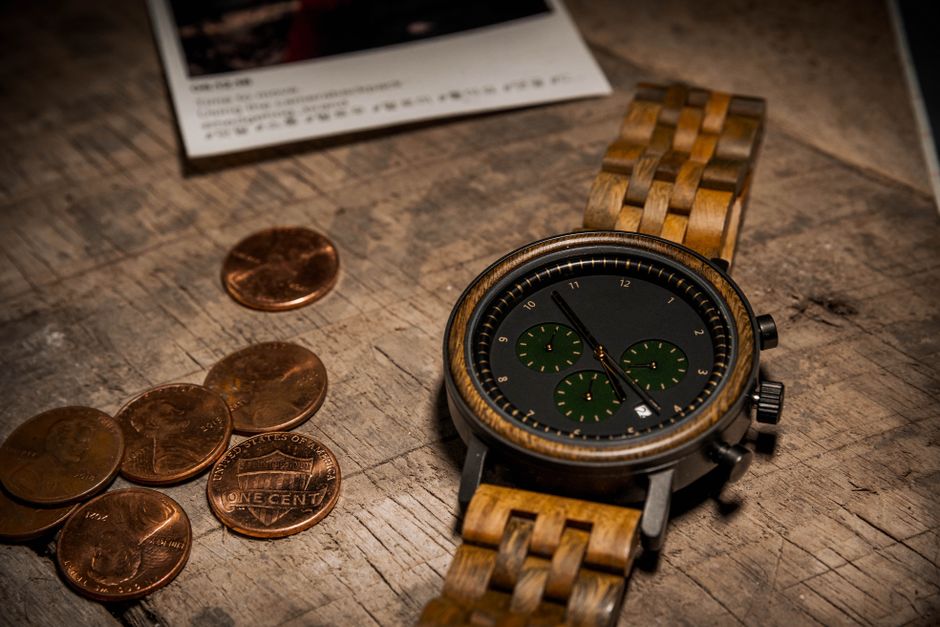 Close-up of a wooden wrist watch and coins on a rustic table, evoking a vintage still life vibe.