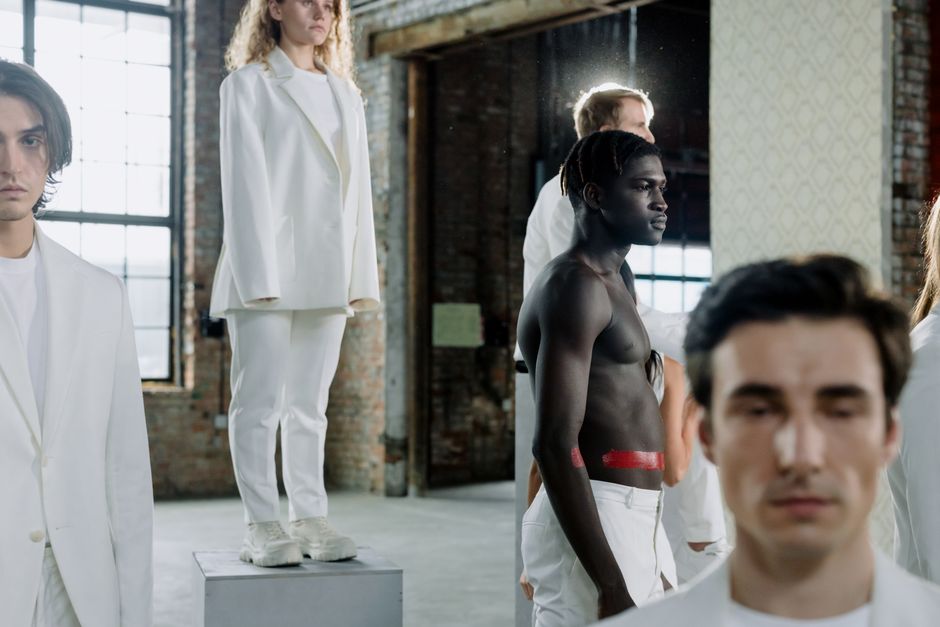A group of diverse individuals standing in an industrial location, showcasing unique fashion and expressions.