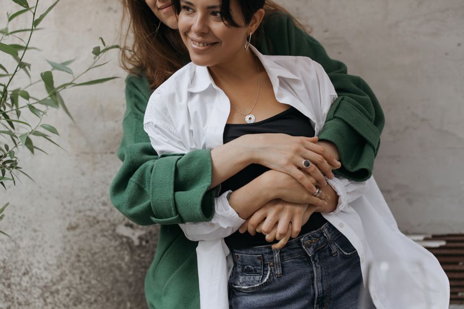 Smiling couple embracing warmly, celebrating love and togetherness on an outdoor backdrop.