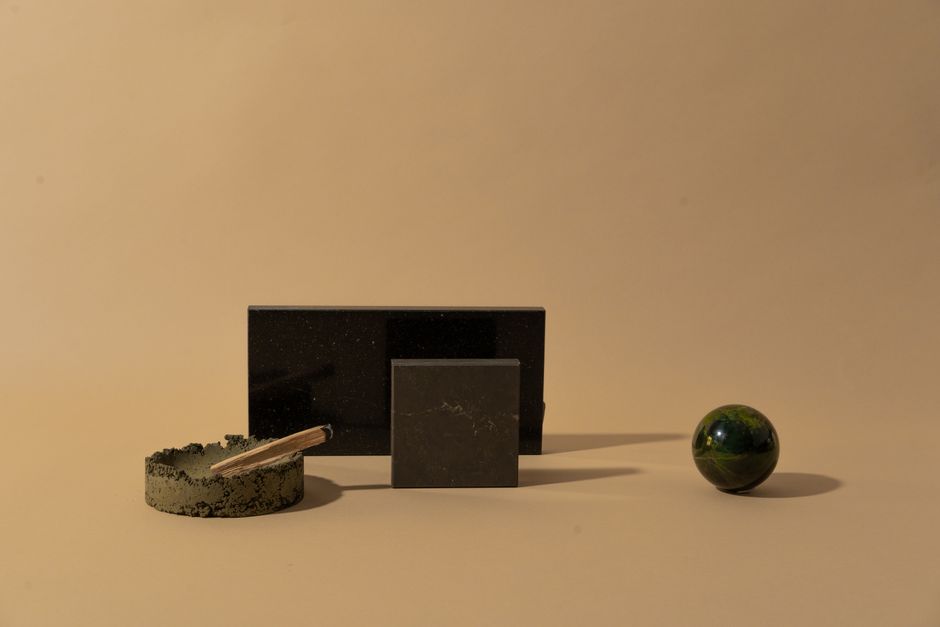 Minimalist still life featuring geometric shapes and a palo santo stick against a beige background.
