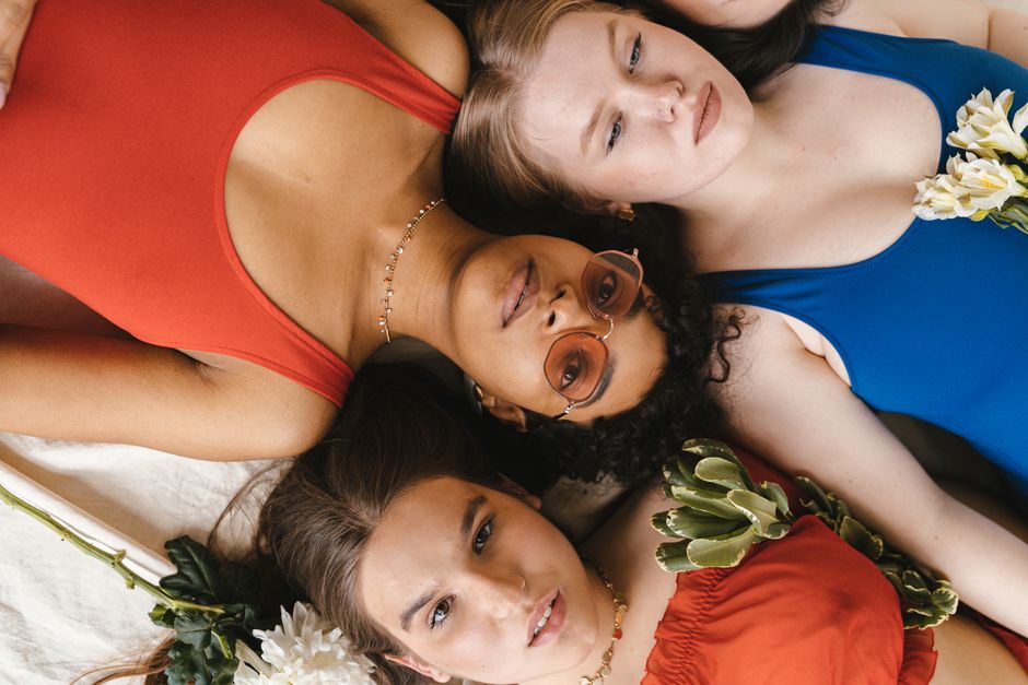 Diverse group of women in colorful swimwear with flowers, creating a vibrant and artistic composition.