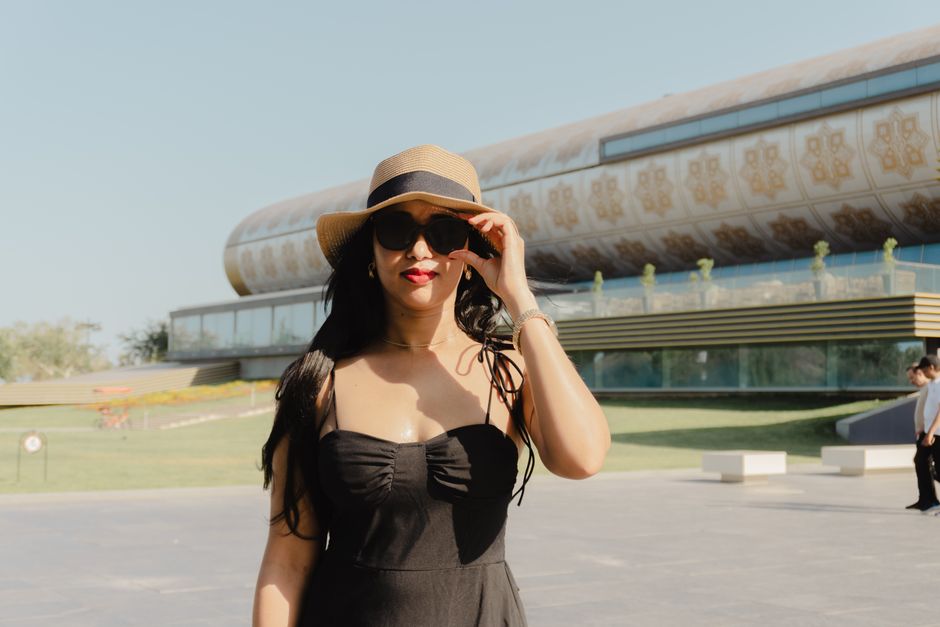 Fashionable woman in black dress poses at Heydar Aliyev Center in Baku, Azerbaijan, during a sunny day.