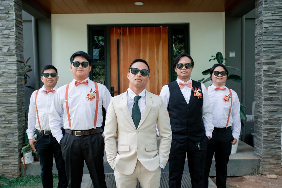 Groom and groomsmen posing outdoors in stylish suits and sunglasses, exuding elegance and modern fashion.