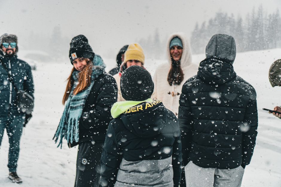 A group of friends bundled up enjoying snowfall in a winter landscape.