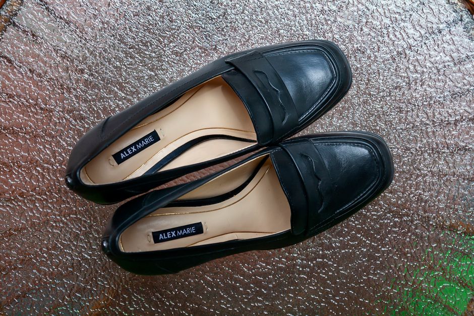 Overhead shot of black leather loafers on textured glass surface, showcasing stylish footw