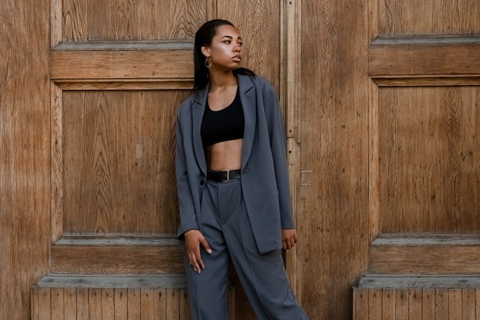 Confident woman in a fashionable suit posing outdoors by a wooden door.