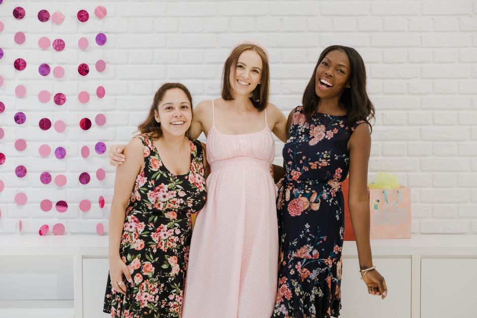Three women celebrating a baby shower, showcasing friendship and happiness indoors.