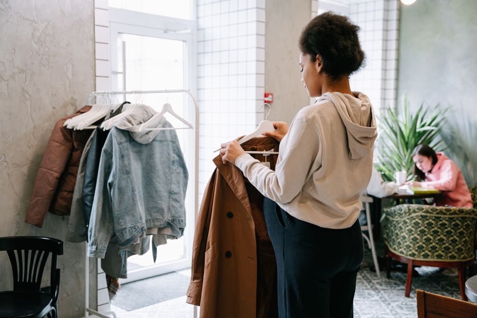 A woman browsing coats indoors, creating a cozy shopping atmosphere.