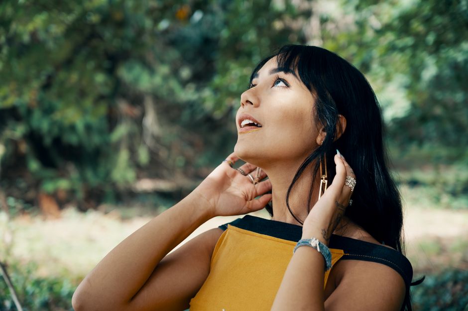Portrait of a young woman looking up while posing outdoors in a forest.