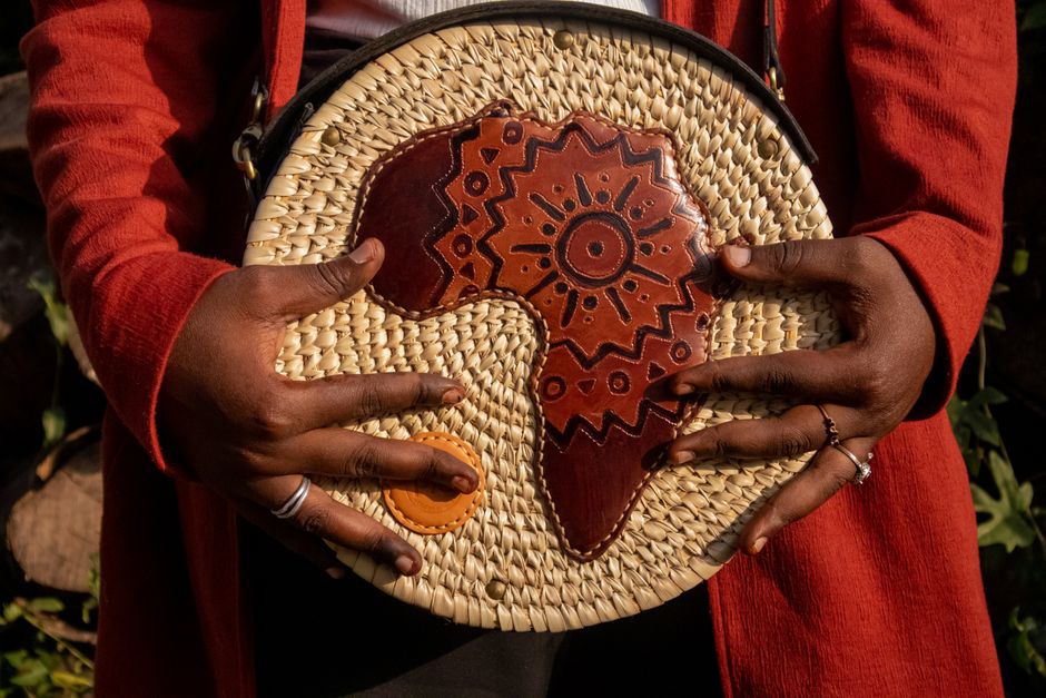 Close-up of hands holding a handcrafted woven bag with African motif design.