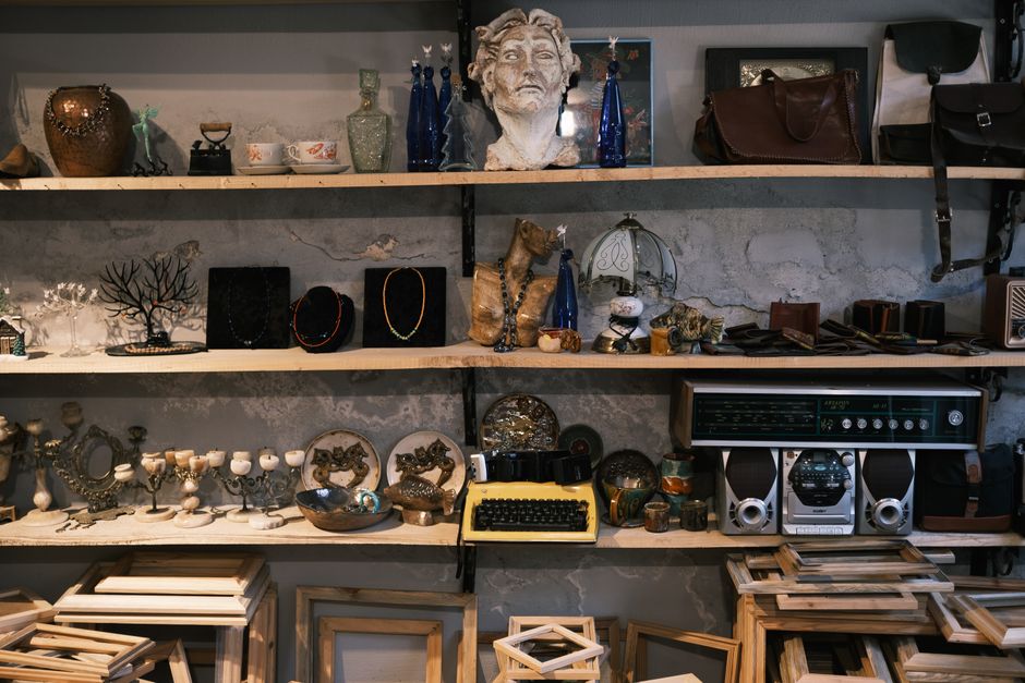 A vintage shop shelf filled with eclectic antiques, decor items, and a typewriter.