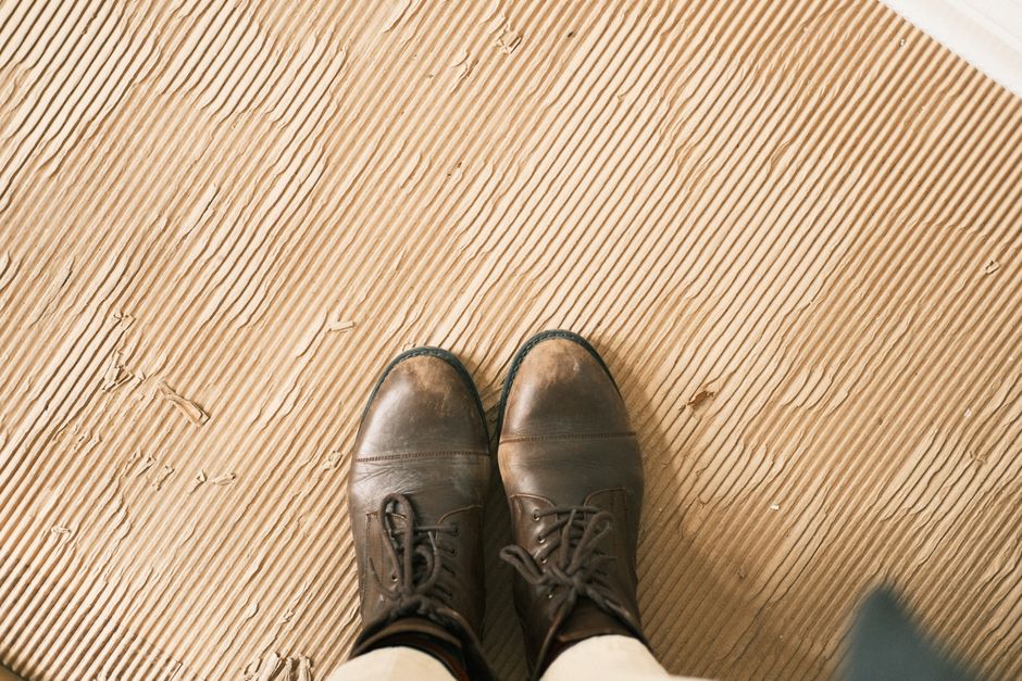 Top-down view of brown leather boots standing on a corrugated brown surface.