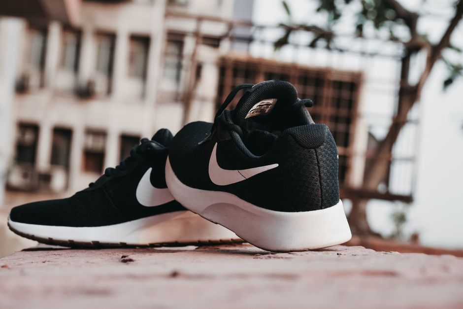 Close-up of black sneakers on urban pavement in New Delhi, India.