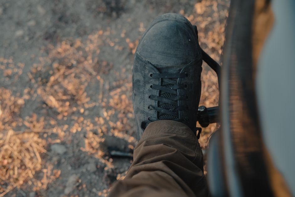 View from above of a motorcyclist's foot on a motorcycle pedal on a rural dirt road.